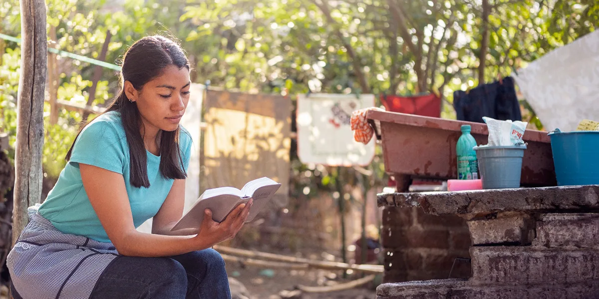 A young woman reading the Bible outdoors